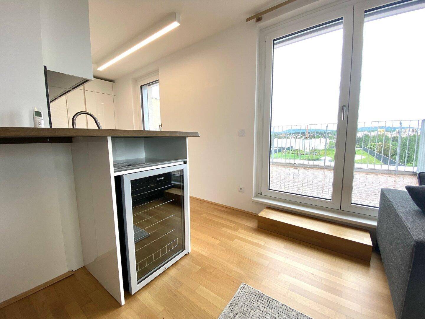 Küchenzeile mit Bartheke, integriertem Weinkühler und Zugang zum Balkon.