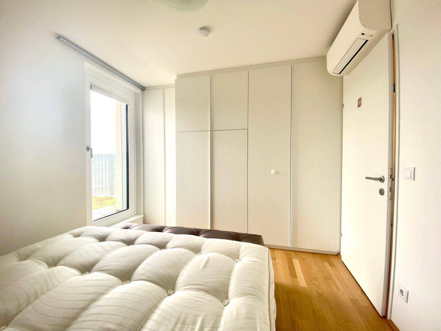 Schlafzimmer mit Einbauschränken, Holzboden und Klimaanlage für Komfort.