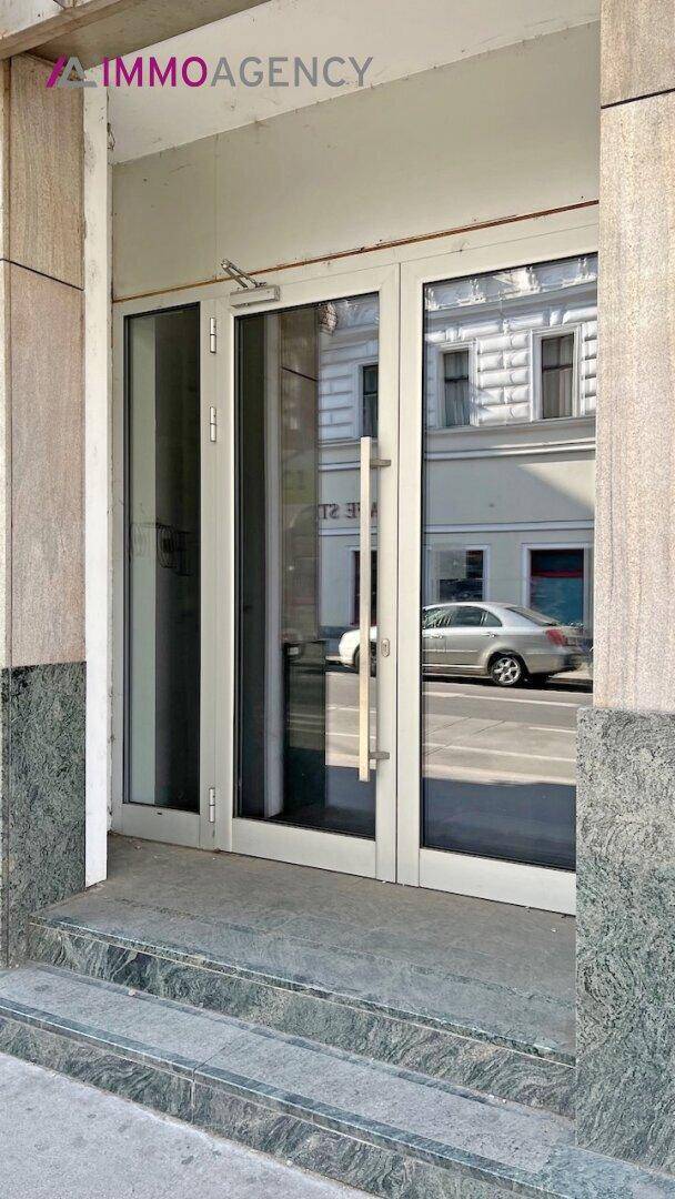 Eingangsbereich eines Gebäudes mit Glastüren und Marmorverkleidung.