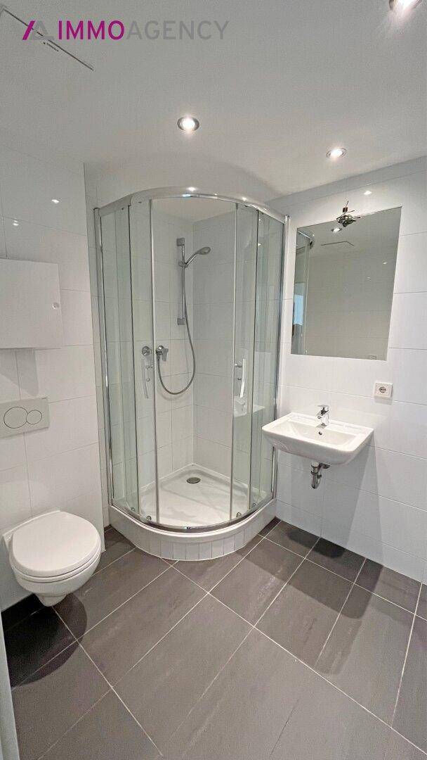 Modernes Badezimmer mit Eckdusche, wandhängendem WC und Waschbecken.