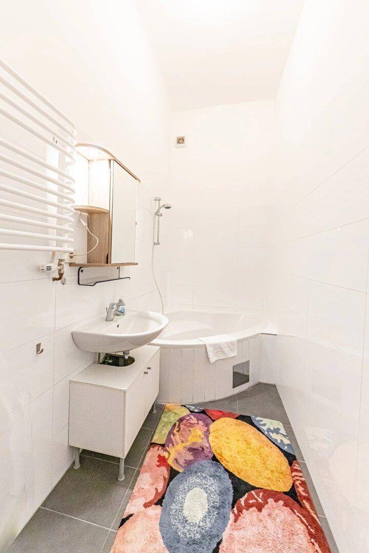 Modernes Badezimmer mit Badewanne, Waschbecken und beheiztem Handtuchhalter.