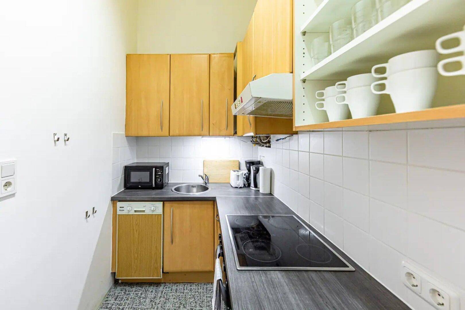Kompakte Küche mit Holzfronten, Spüle und allen notwendigen Geräten.