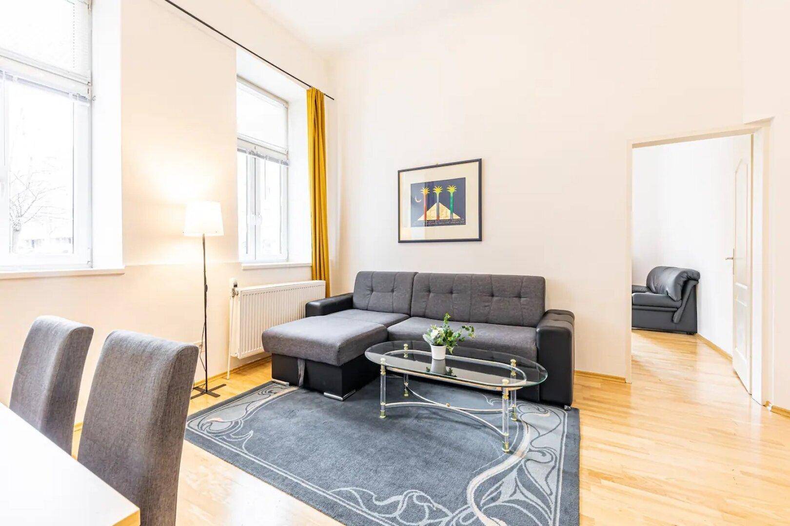 Heller Wohnbereich mit Esstisch, Sofa und Blick in einen angrenzenden Raum.