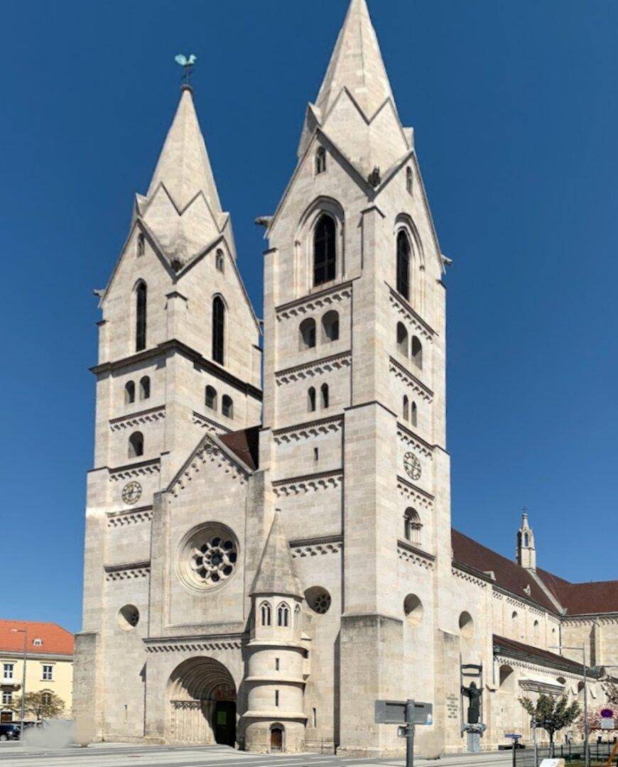 Beeindruckende gotische Kirche mit zwei hohen Türmen und detaillierter Fassade unter blauem Himmel.