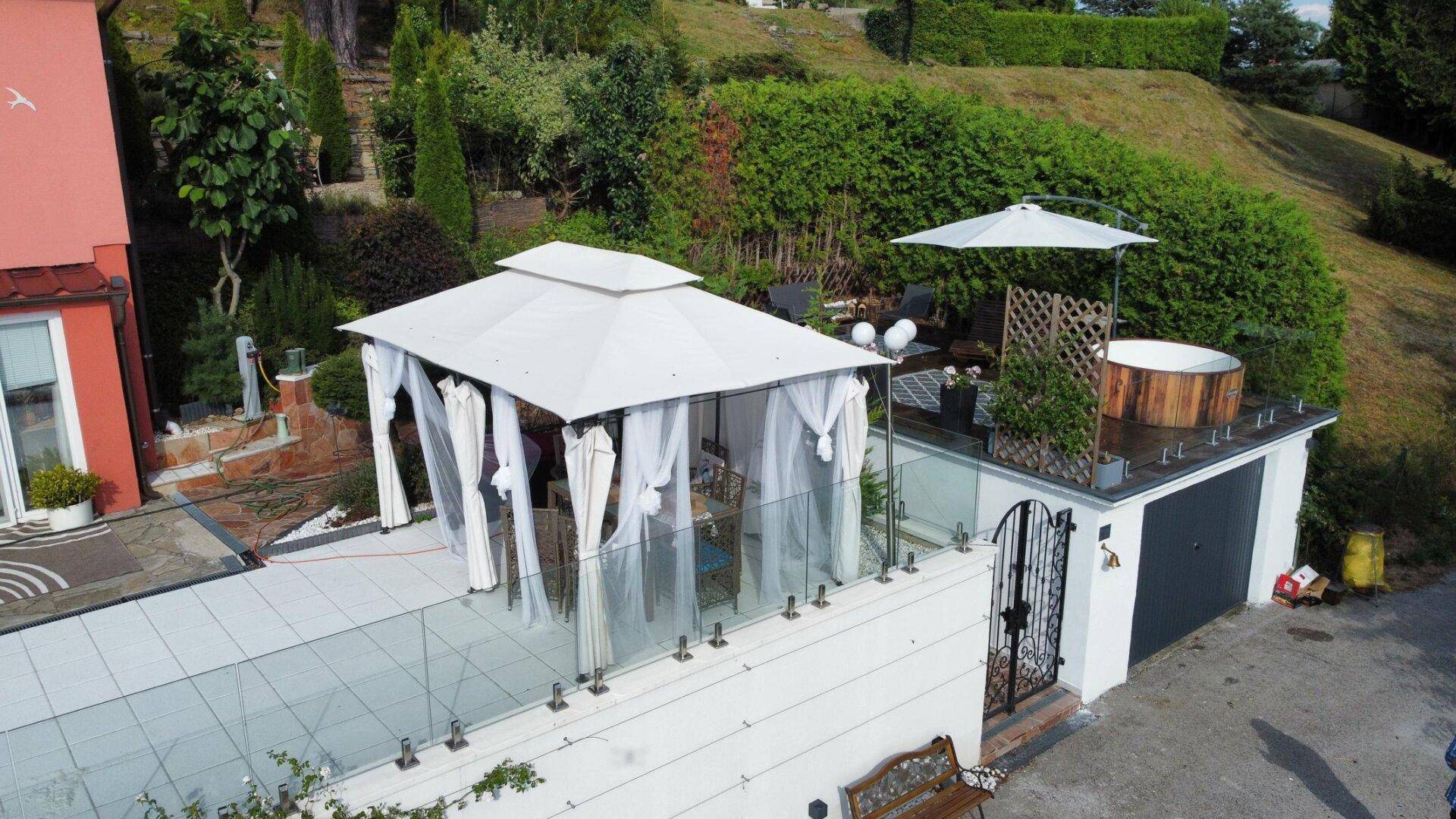 Geräumige Terrasse mit einem eleganten Pavillon, einem Whirlpool und Blick auf die grüne Umgebung.