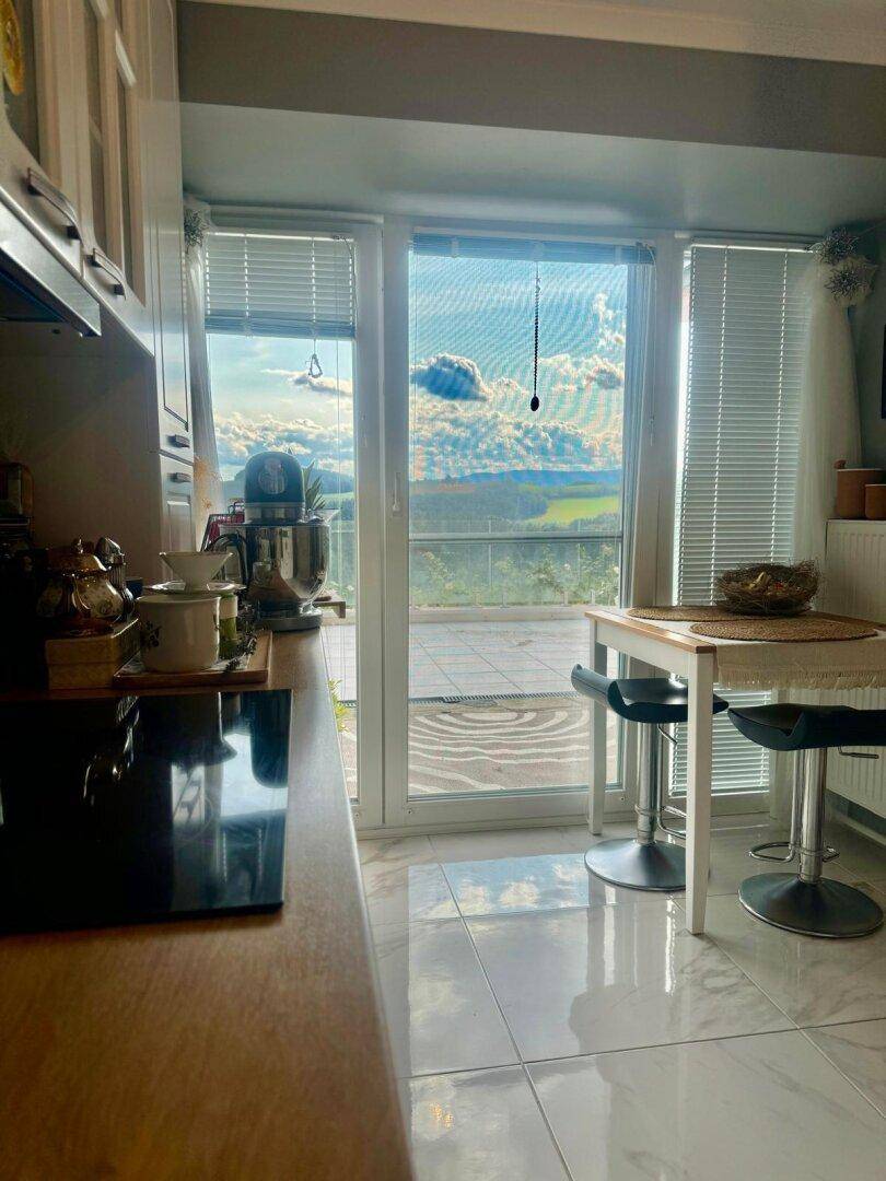 Helle Küche mit Essbereich, modernen Geräten und weitem Blick in die Landschaft.