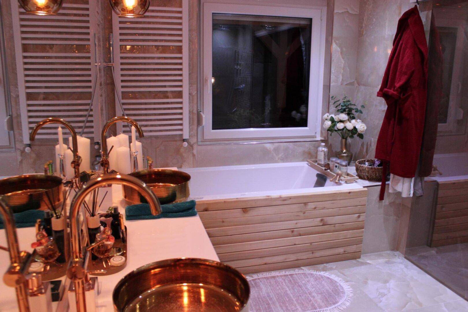 Stilvolles Badezimmer mit Doppelwaschbecken, Badewanne und warmen Kupferarmaturen.
