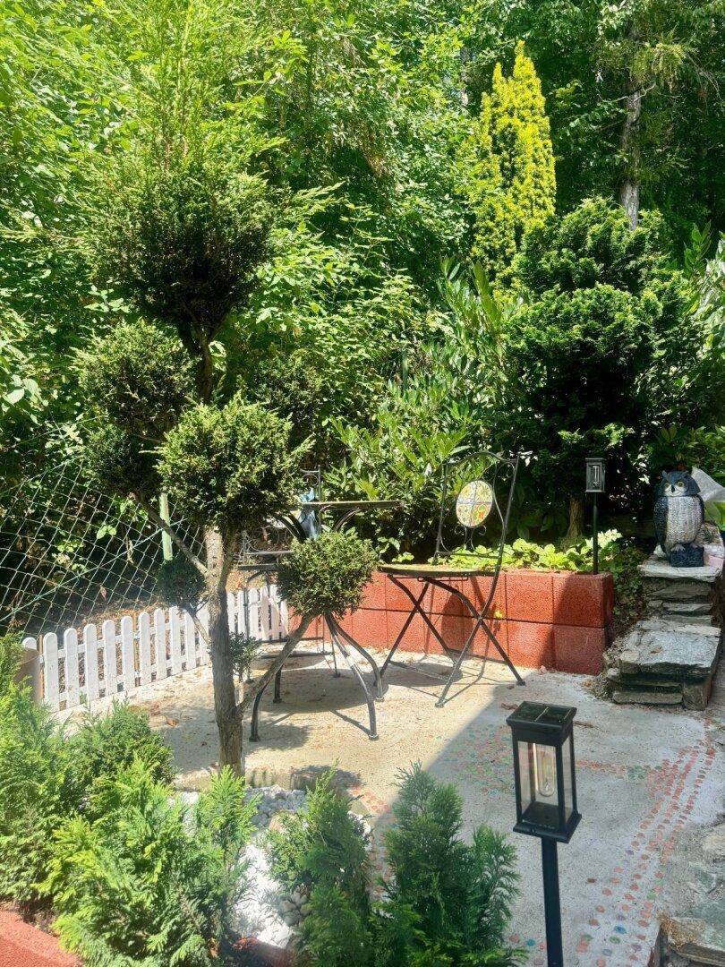 Kleiner, liebevoll gestalteter Gartenbereich mit Sitzgelegenheit und dekorativen Pflanzen.