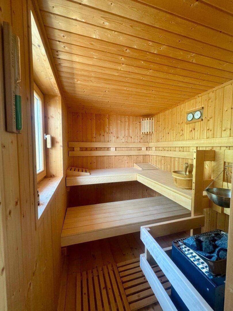 Traditionelle Holzsauna mit mehreren Bänken und einem Saunaofen für Entspannung.