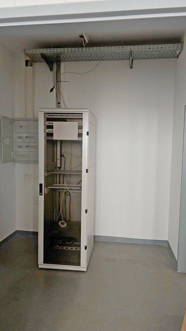 Technikraum mit Serverschrank und Kabeltrassen an der Decke.