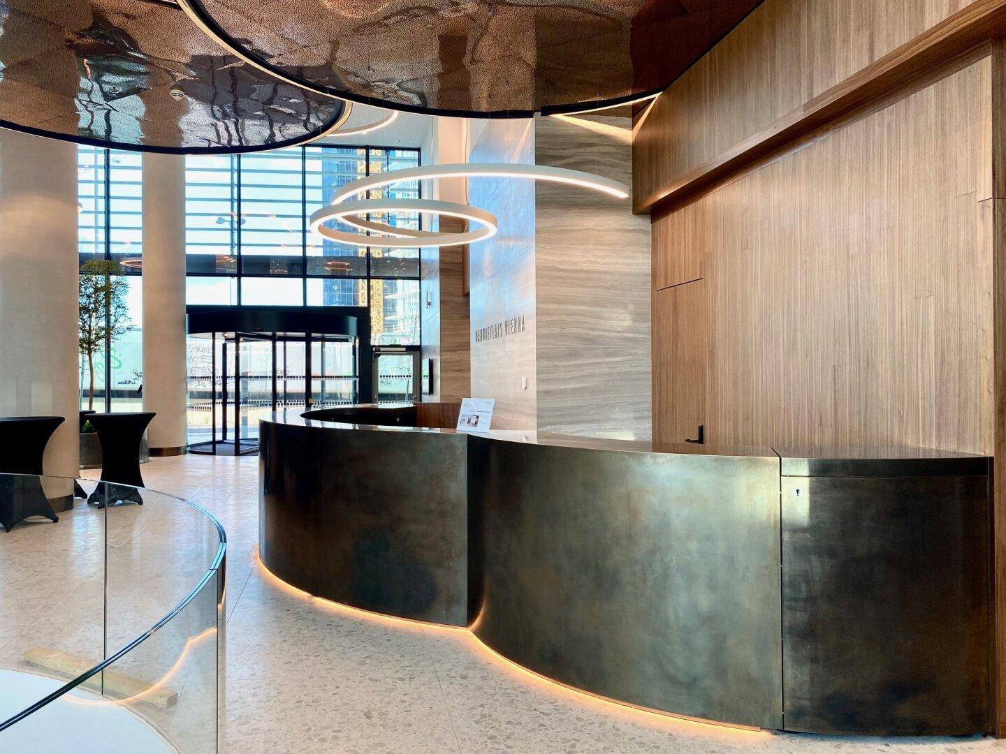 Luxuriöser Empfangsbereich mit moderner Beleuchtung, Holzverkleidungen und eleganten Theken.