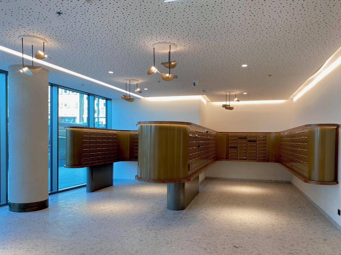 Stilvoller Postraum mit vielen Schließfächern und moderner Beleuchtung in einem Wohngebäude.