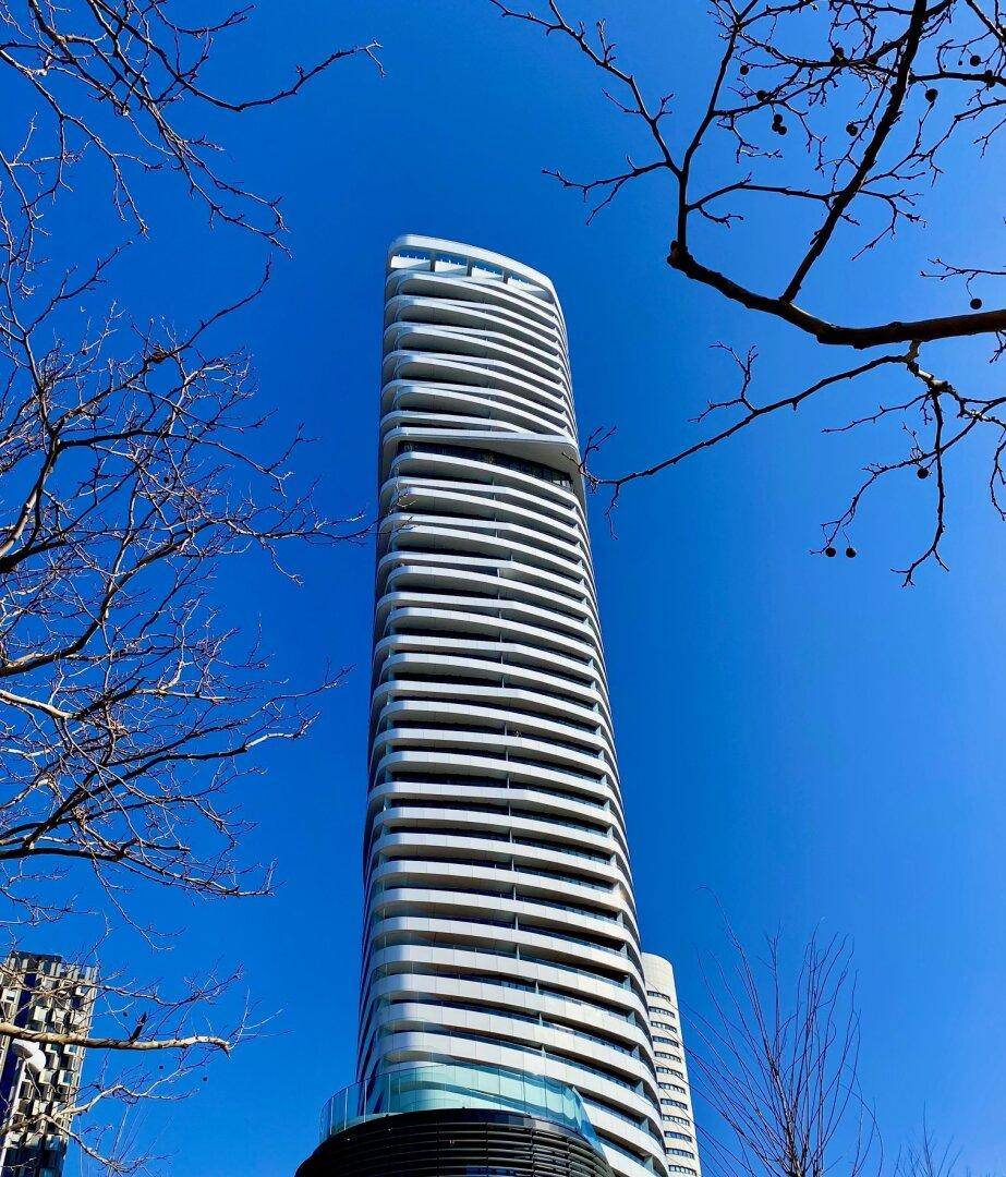 Hohes, modernes Gebäude mit geschwungenen Balkonen unter einem strahlend blauen Himmel.