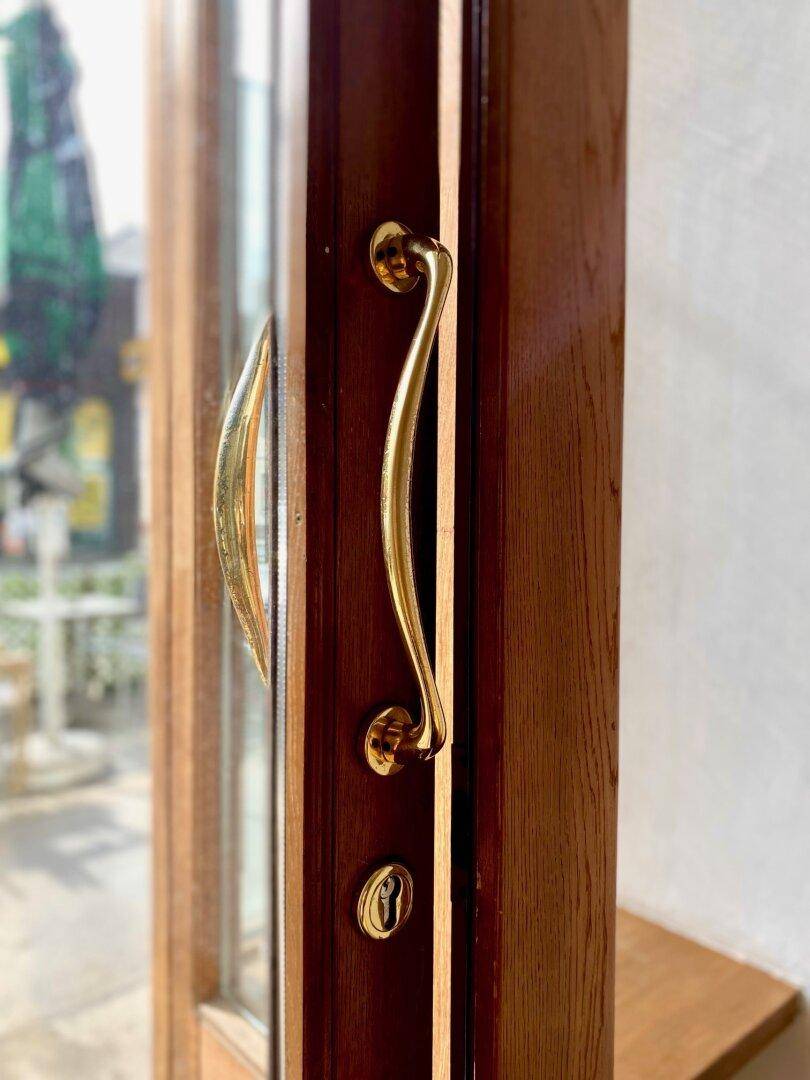 Nahaufnahme eines eleganten goldenen Türgriffs an einer Holztür mit Glaseinsatz.