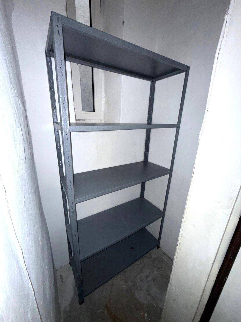 Kleiner Abstellraum mit Metallregal und Fenster, ideal für zusätzlichen Stauraum.