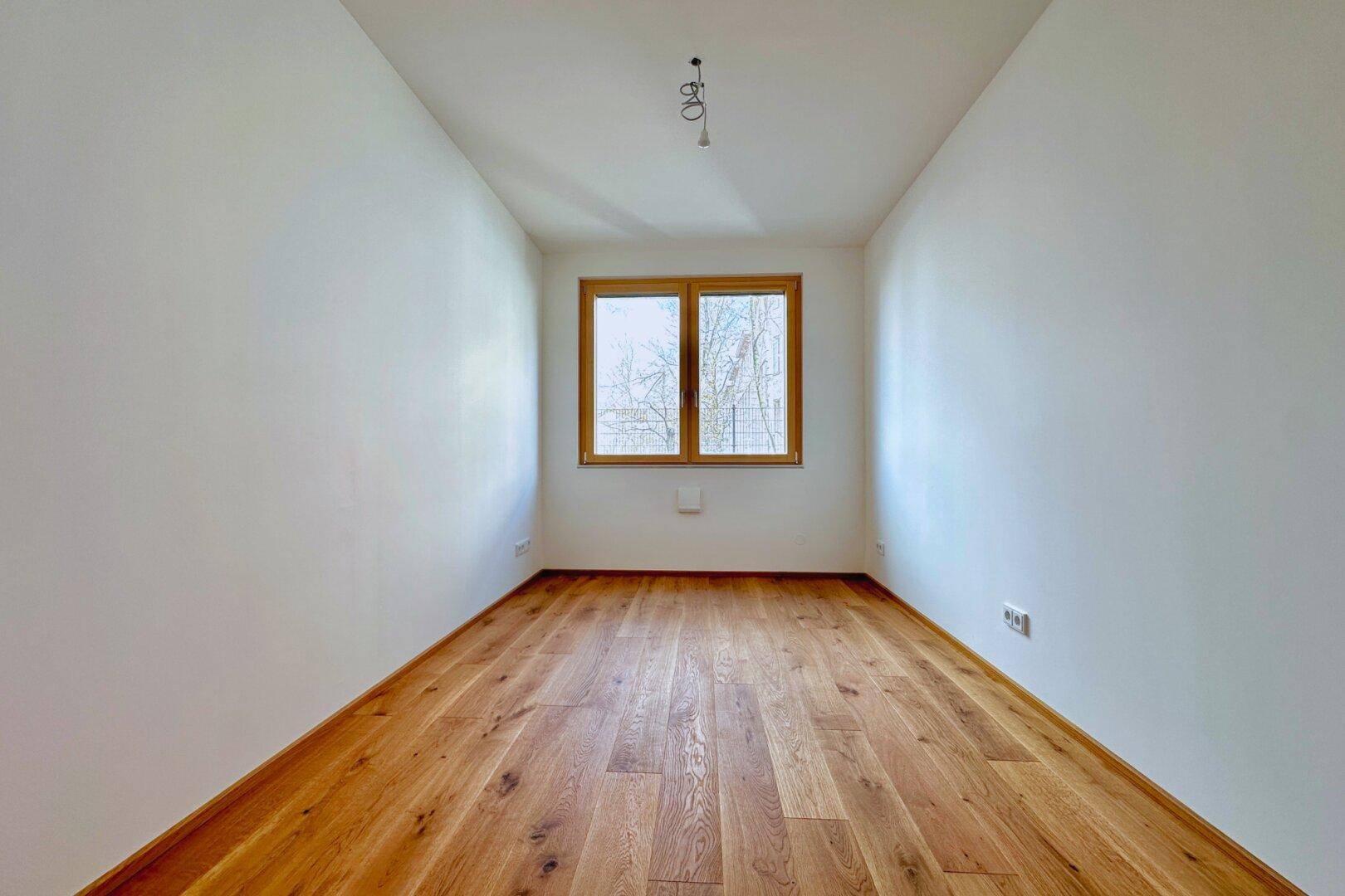 Unmöbliertes Schlafzimmer mit Holzboden und weiß gestrichenen Wänden, bereit zur individuellen Gestaltung.