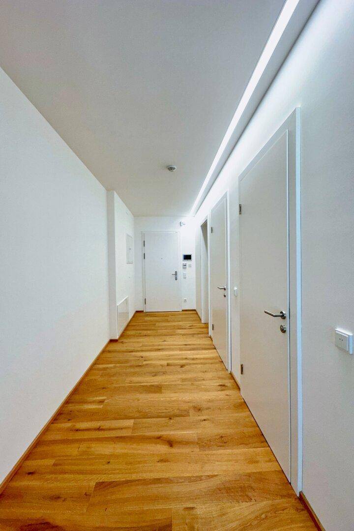 Heller Flur mit Holzboden und modernen weißen Türen, der zu den verschiedenen Räumen führt.