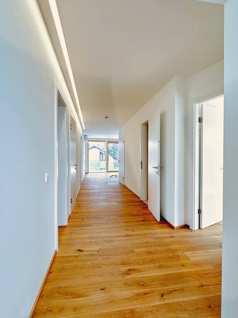 Heller Flur mit Eichenparkett und integrierter Deckenbeleuchtung, führt zu weiteren Räumen.