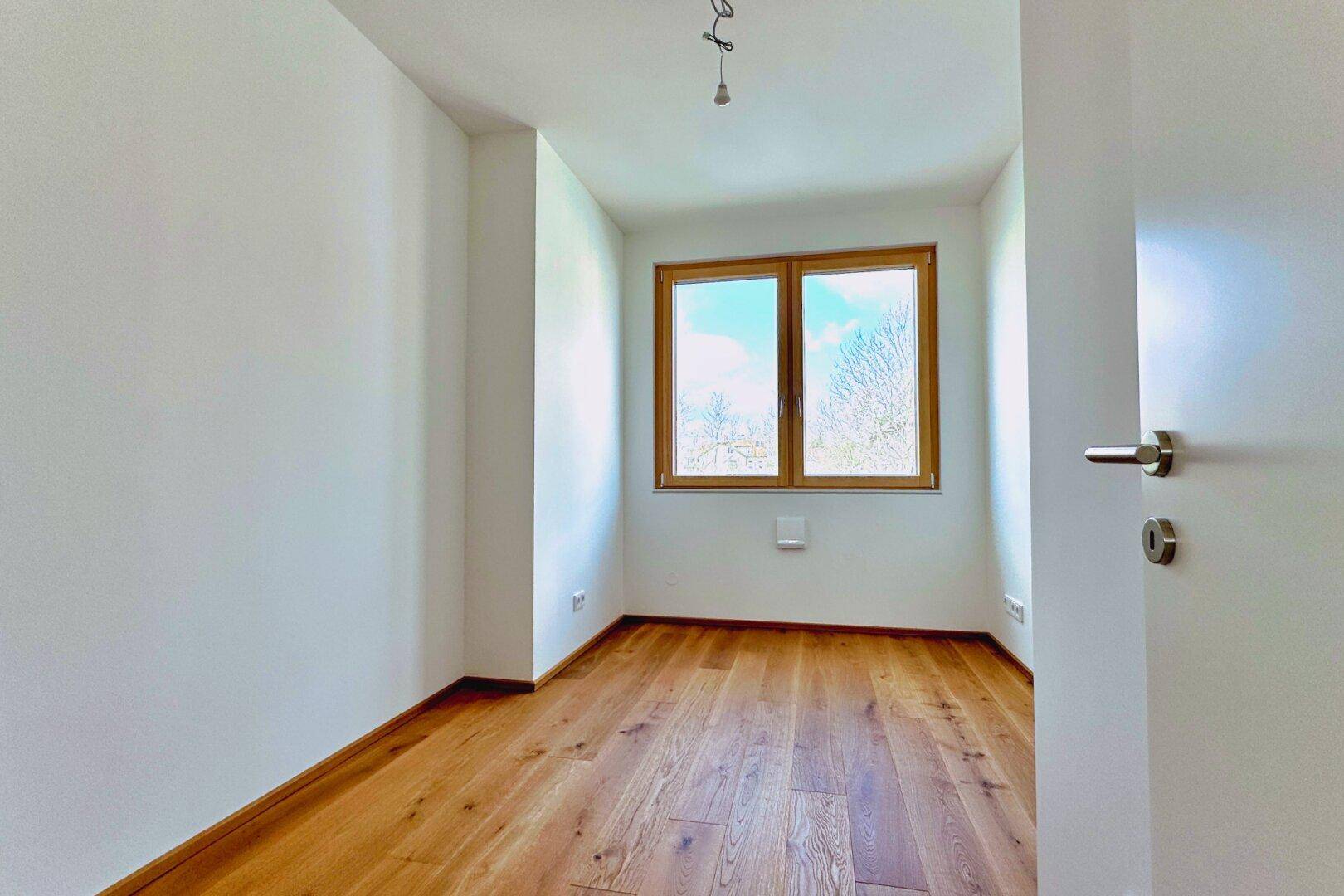 Kleiner, heller Raum mit Parkettboden und Fenster, ideal als Kinder- oder Arbeitszimmer.