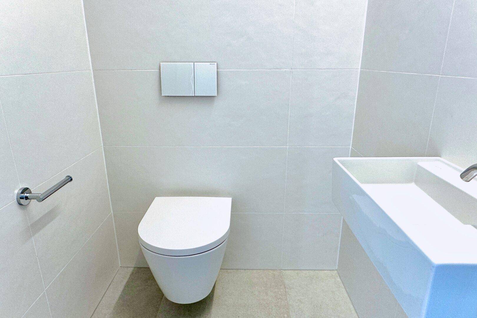 Modernes Gäste-WC mit wandhängender Toilette und stilvollem Waschbecken.