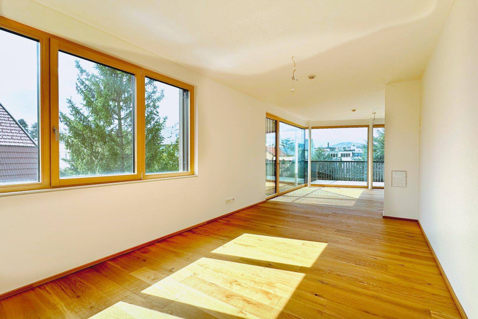 Heller Wohnraum mit großen Fenstern und Eichenparkett, bietet viel Tageslicht und Ausblick.