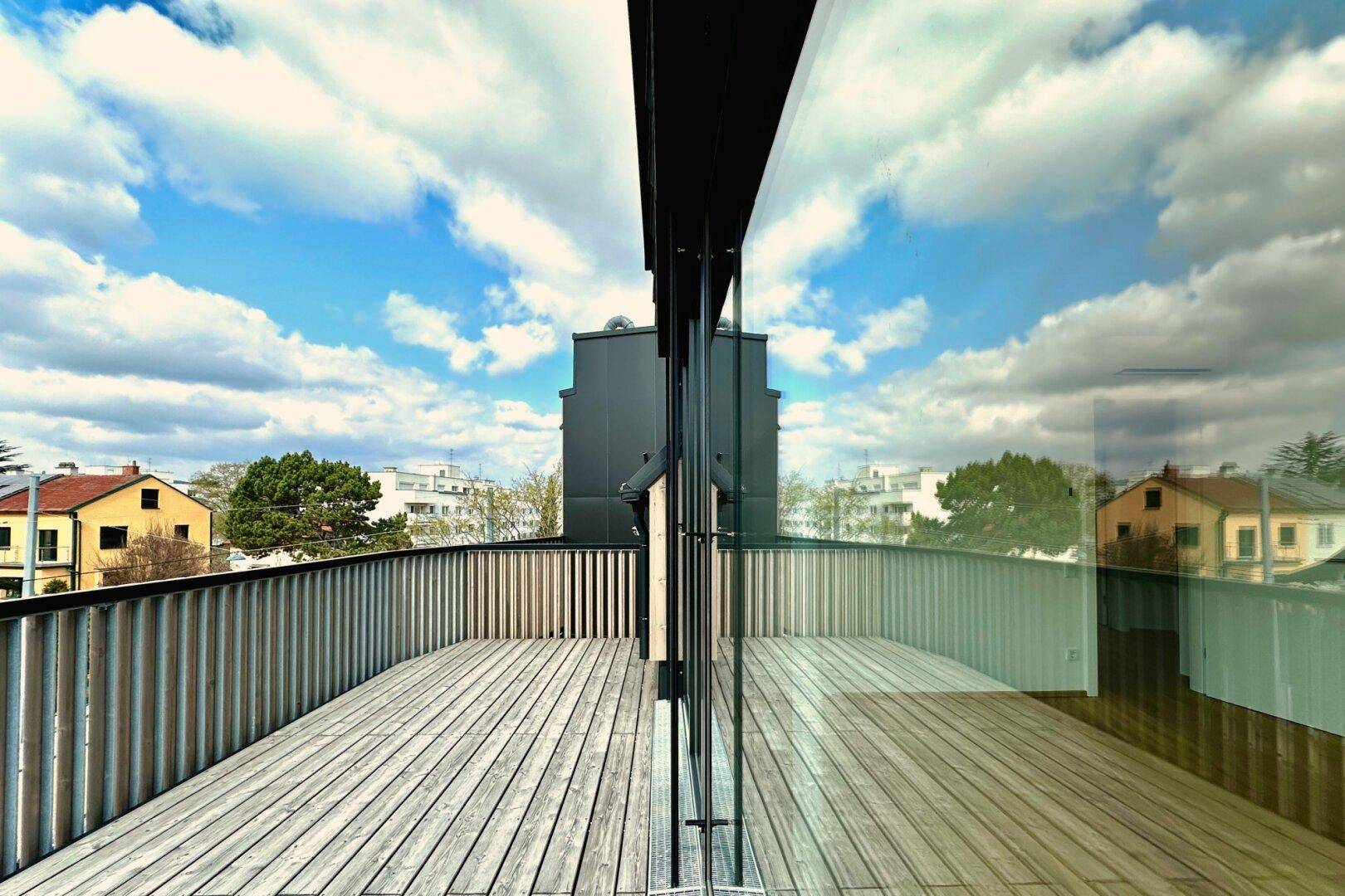 Geräumige Terrasse mit Holzboden und moderner Brüstung, bietet einen weiten Blick über die Umgebung.
