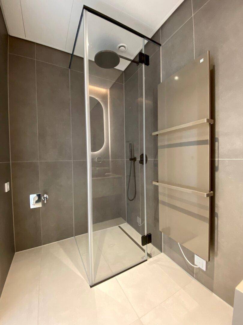Elegante Duschkabine mit Regendusche und modernen grauen Fliesen in einem stilvollen Badezimmer.