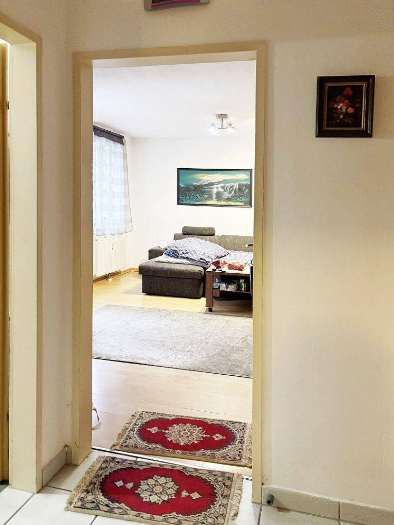 Blick durch einen Türrahmen in das helle Wohnzimmer mit Holzboden.