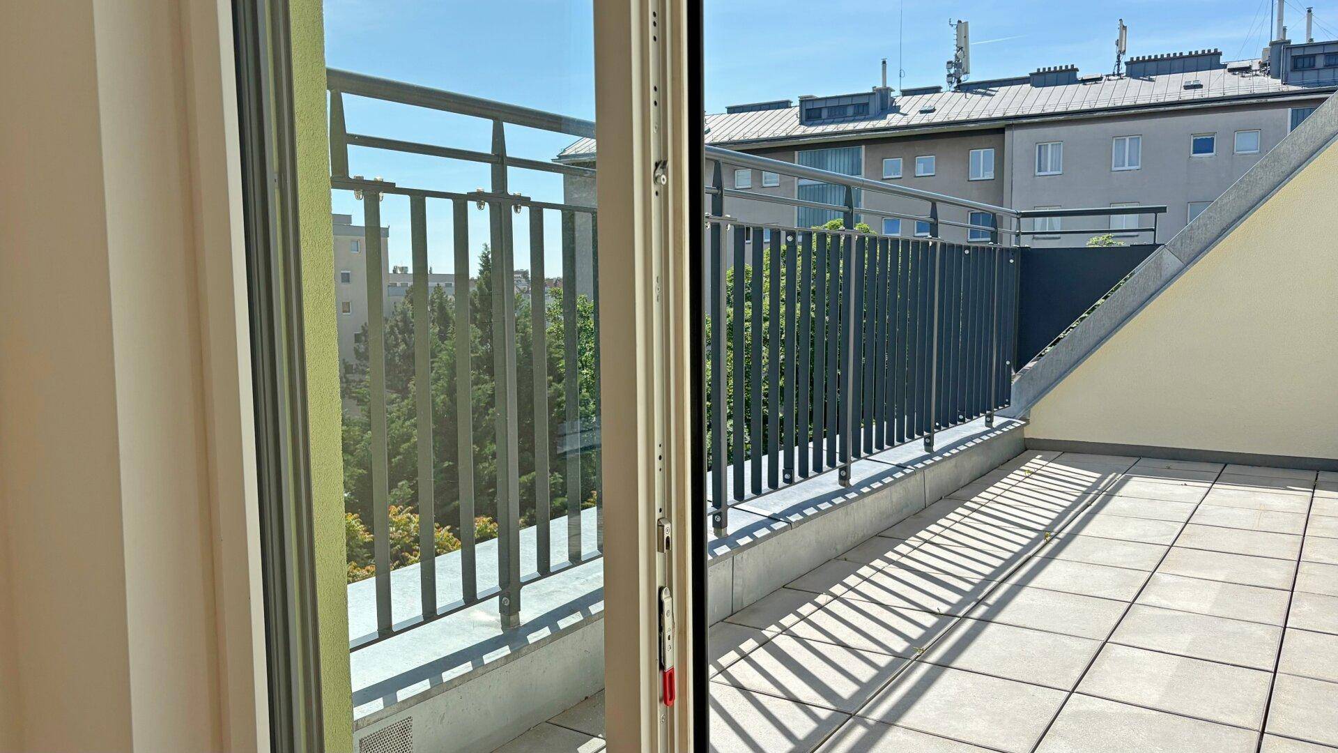 Große geflieste Terrasse mit Metallgeländer und Blick auf die Dächer der Stadt.