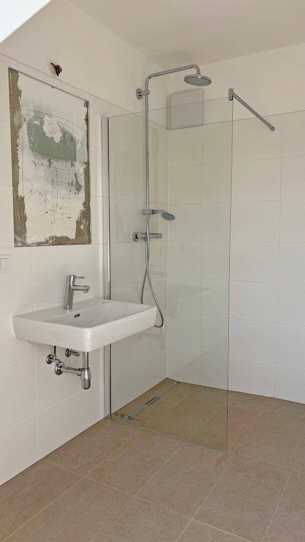 Modernes Badezimmer mit ebenerdiger Dusche, Wandfliesen und Einzelwaschbecken.