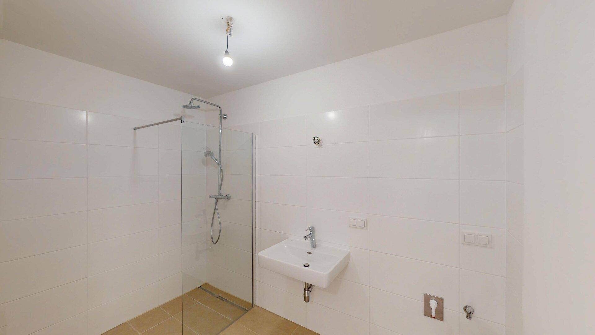 Modernes Badezimmer mit ebenerdiger Dusche, Waschbecken und weißen Wandfliesen.