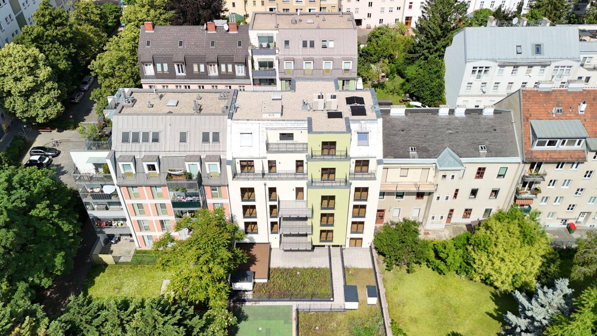 Luftaufnahme einer modernen Wohnanlage mit begrünten Dächern und umliegenden Gebäuden.
