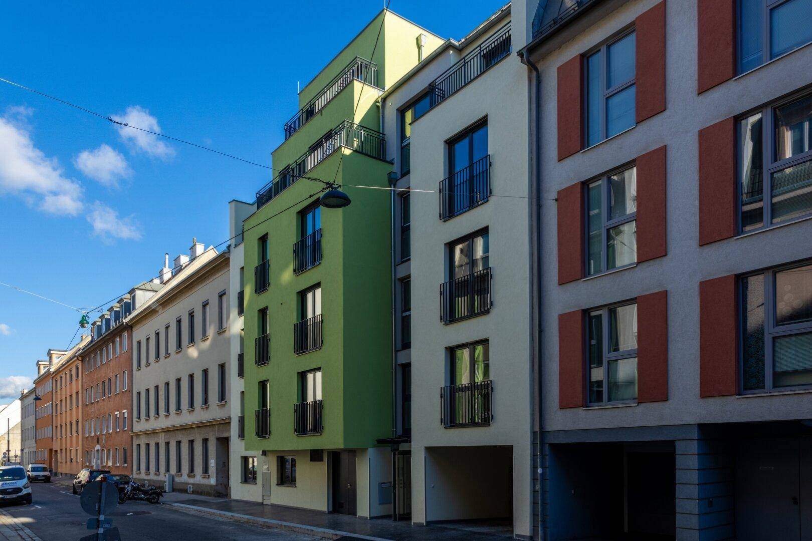 Moderne Wohngebäude mit farbigen Fassaden und Balkonen entlang einer städtischen Straße.