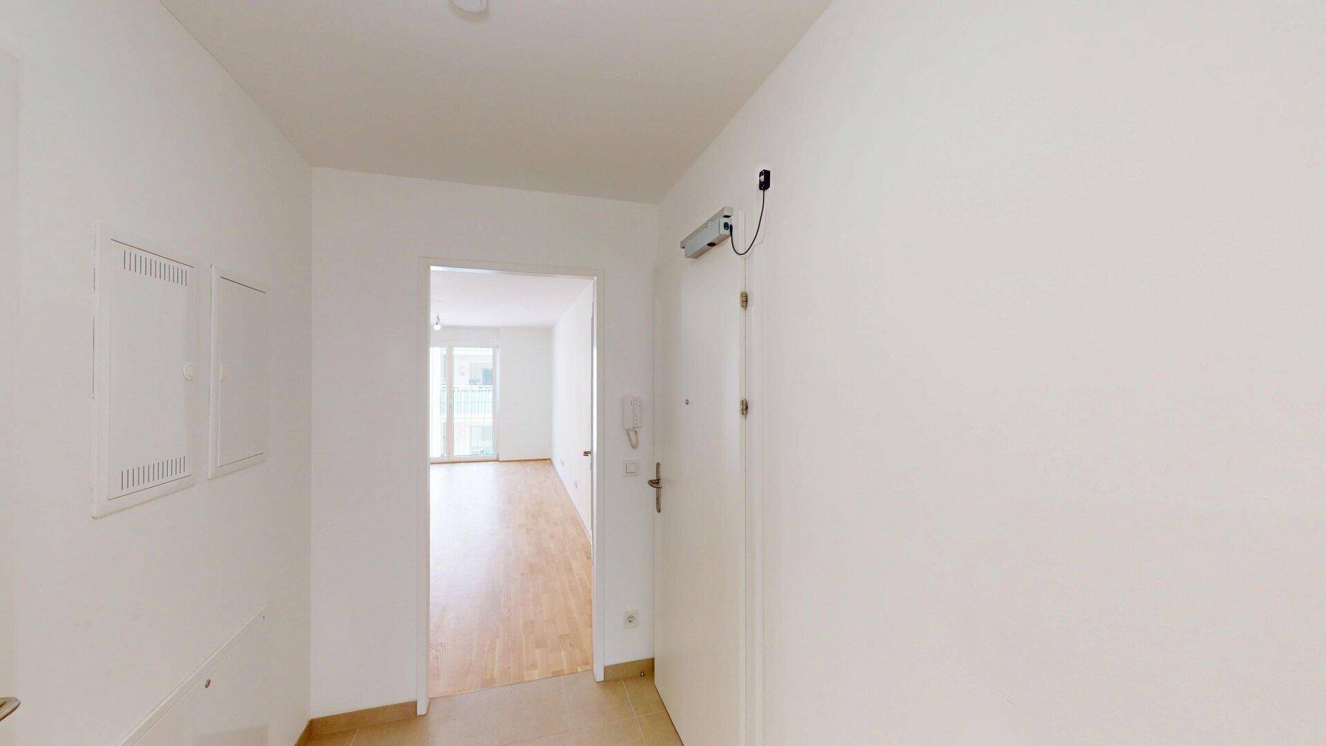 Heller Eingangsbereich mit Fliesenboden und Blick in ein angrenzendes Zimmer.