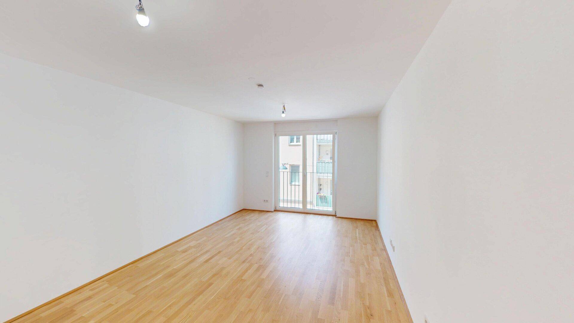 Geräumiges Zimmer mit Parkettboden und Balkonzugang, bereit zur individuellen Gestaltung.