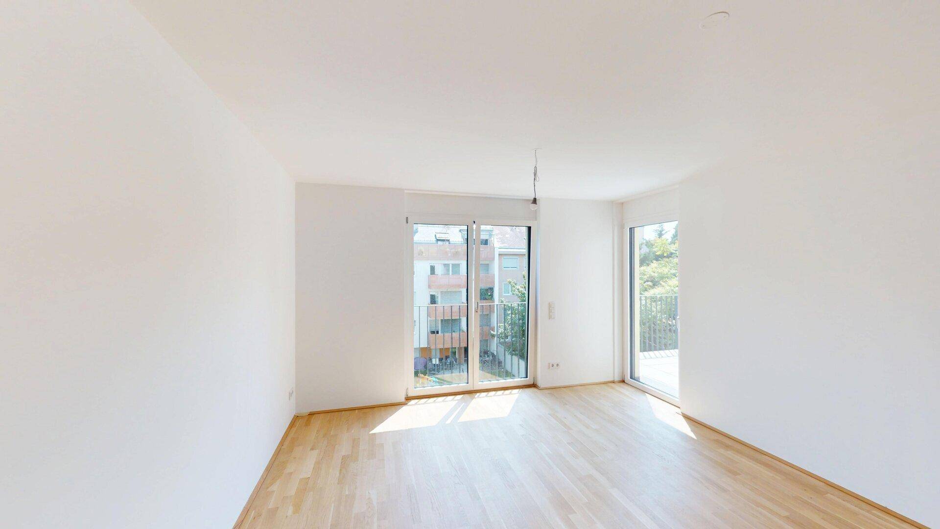 Helles, leeres Zimmer mit Parkettboden und Zugang zu einem Balkon, ideal für individuelle Gestaltung.