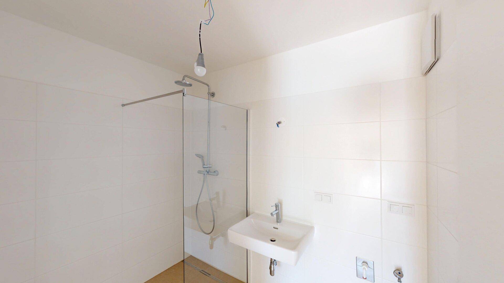Helles Badezimmer mit moderner Dusche, Waschbecken und weißen Fliesen, funktional gestaltet.