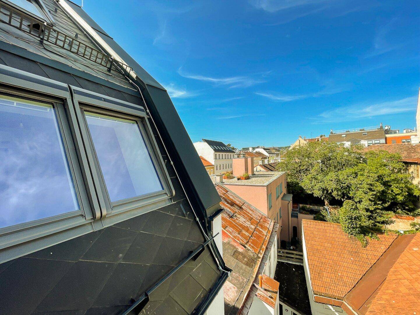 Weitblick über die Dächer der Stadt mit historischer Architektur und blauem Himmel.