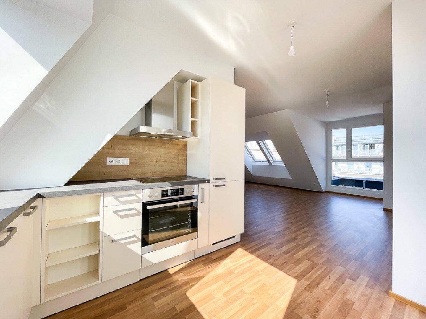 Moderne Einbauküche in einer Dachgeschosswohnung mit Laminatboden und Dachschrägen.