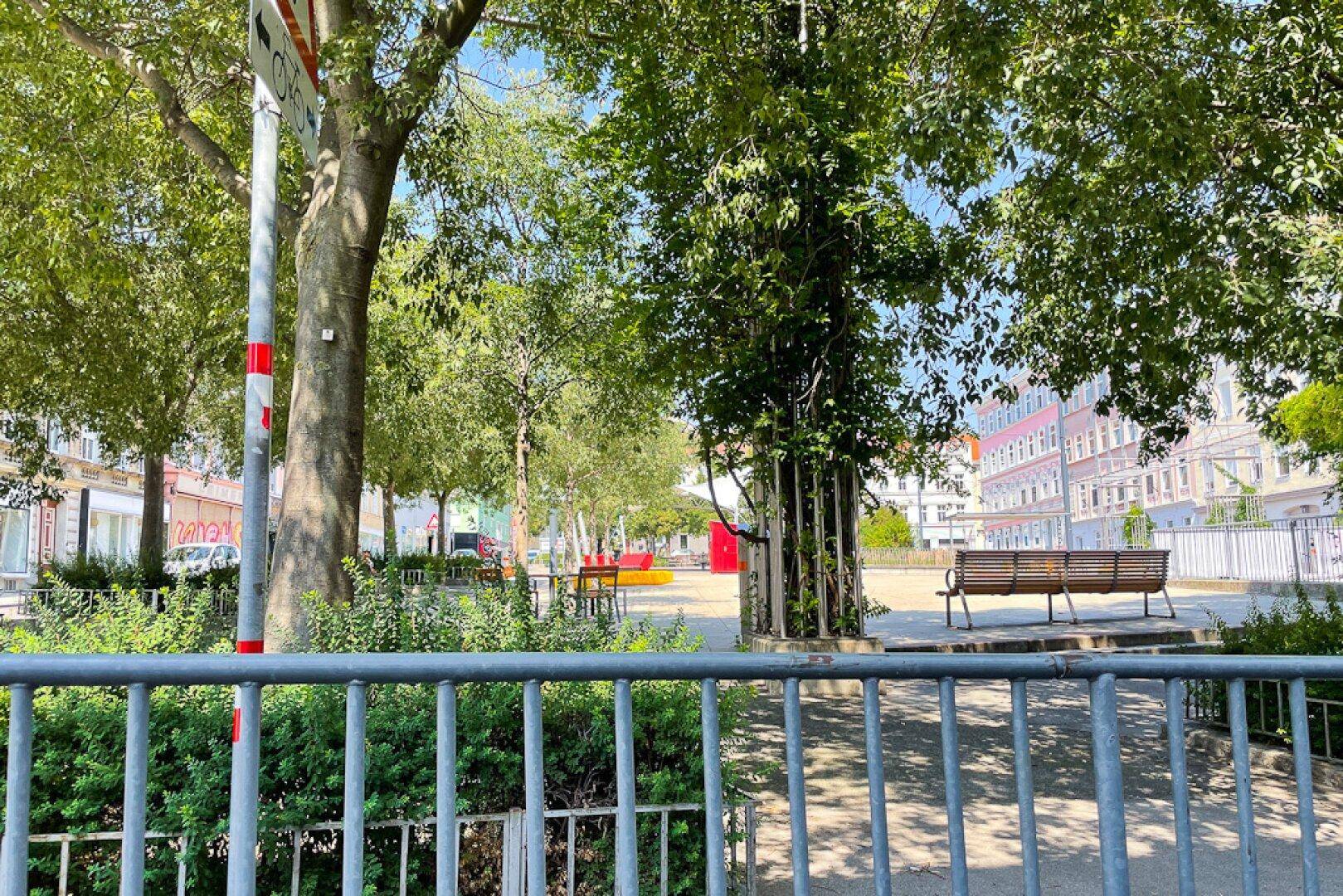 Öffentlicher Park mit Bäumen, Bänken und Grünflächen in der Nähe der Immobilie.