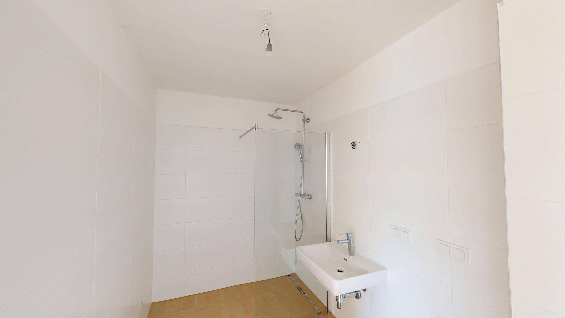 Modernes Badezimmer mit Duschkabine, Waschbecken und hellen Fliesen.