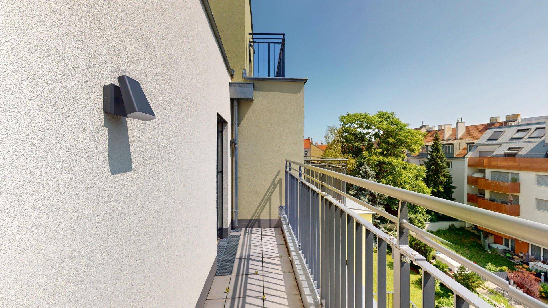 Schmaler Balkon mit Metallgeländer und Blick auf die Nachbarschaft.