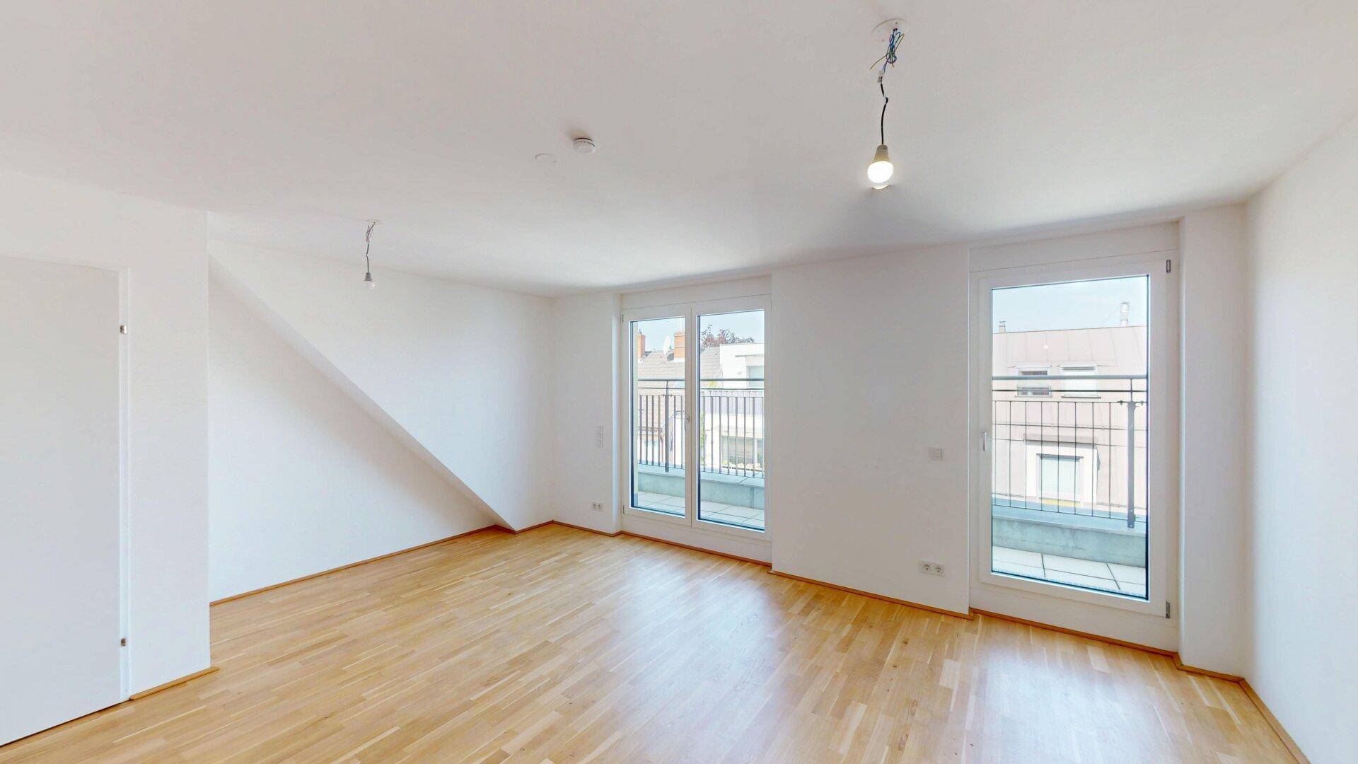 Geräumiges, helles Zimmer mit Holzboden und großen Fenstern, bereit für individuelle Gestaltung.