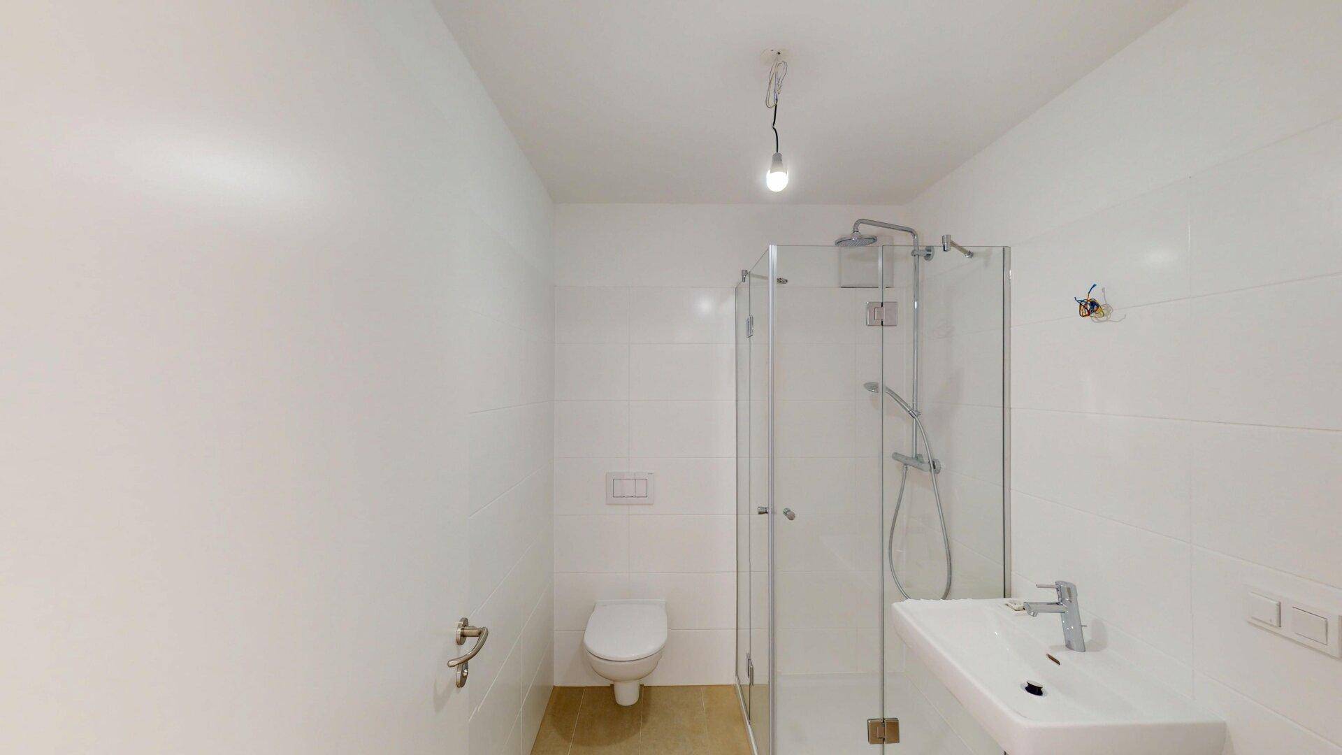 Modernes Badezimmer mit weißen Fliesen, Dusche und wandhängendem WC, sehr gepflegt.