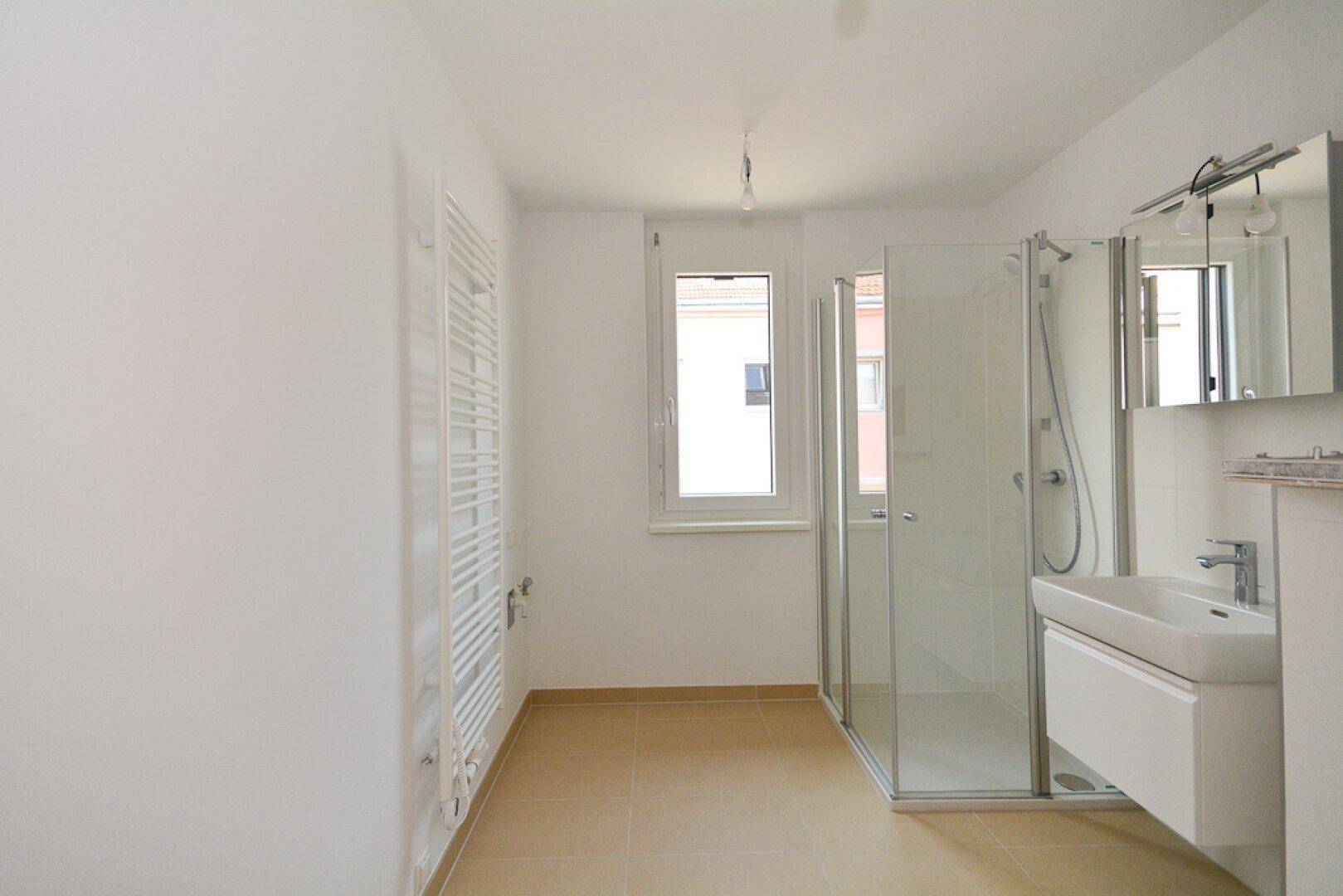 Modernes Badezimmer mit Dusche, Waschbecken, Fenster und beheiztem Handtuchhalter.