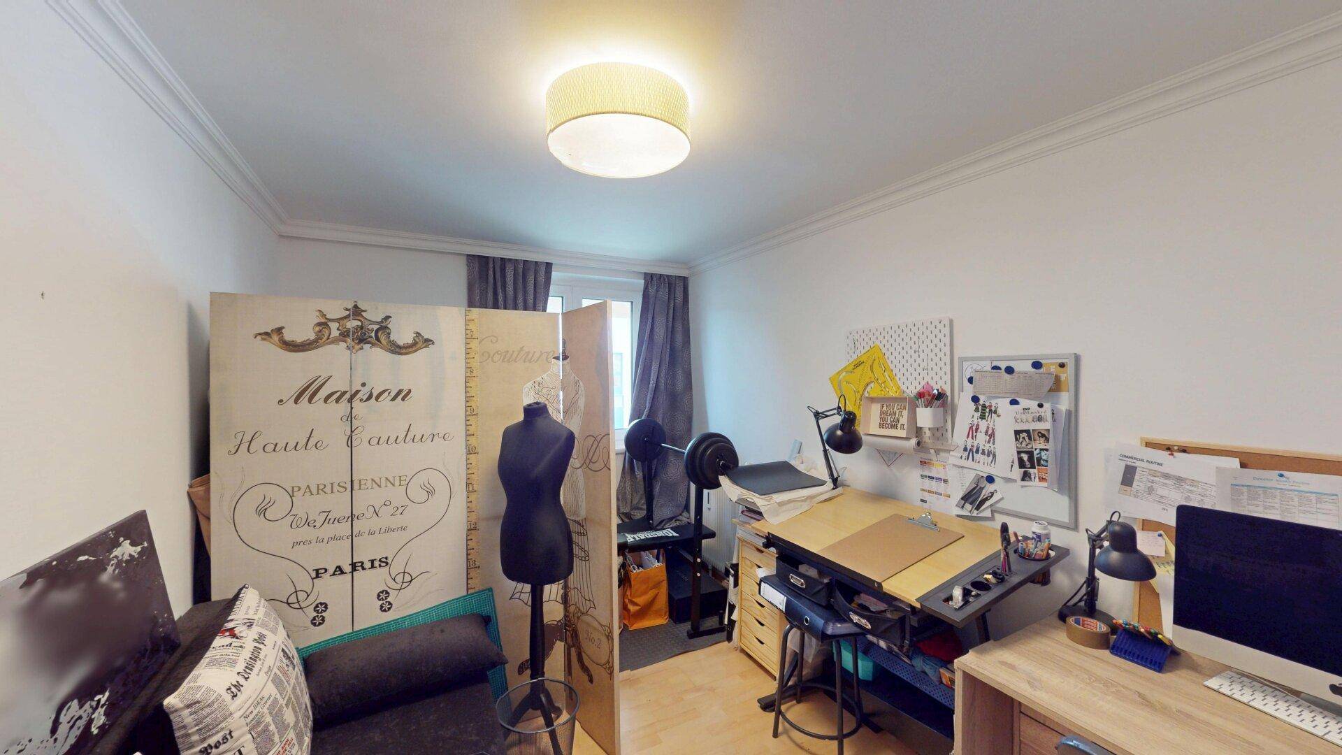 Arbeitszimmer mit Schreibtisch, kreativer Dekoration und Fenster mit Vorhängen.