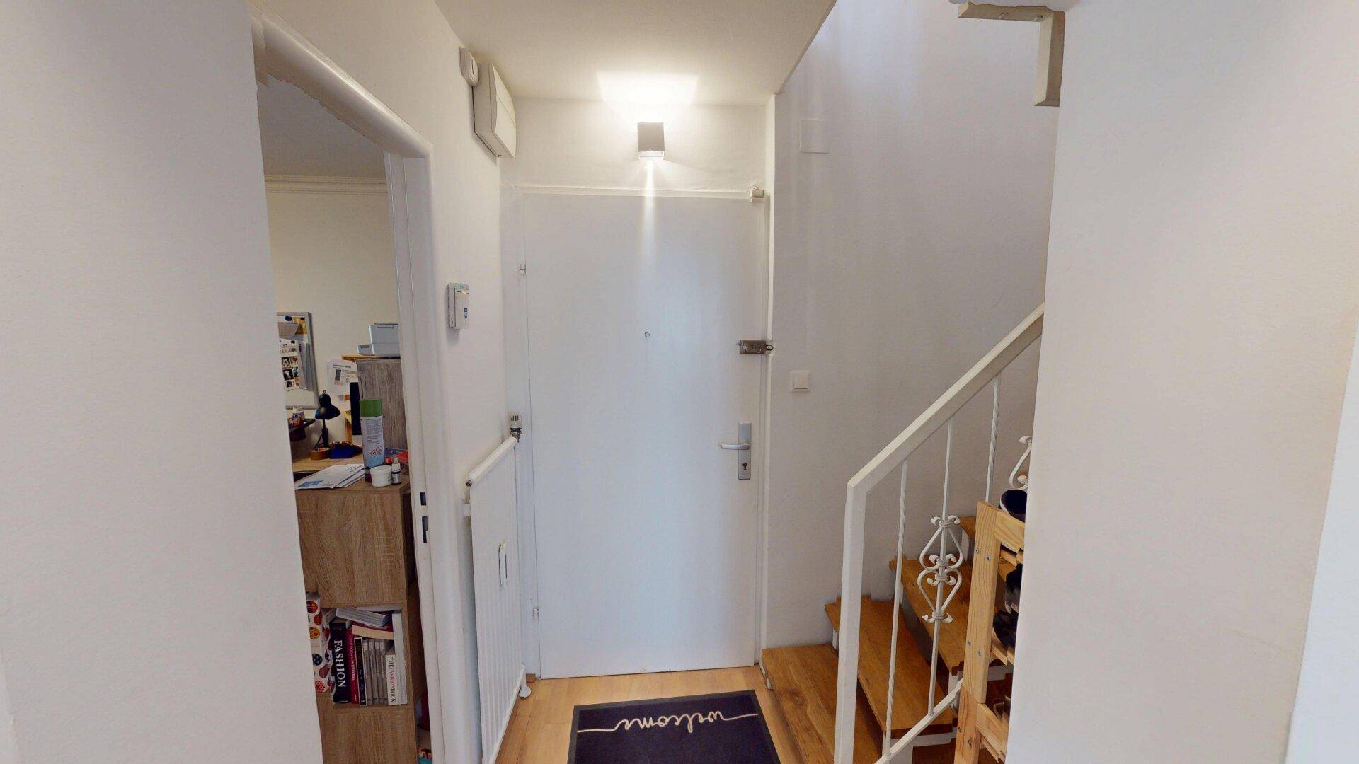 Eingangsbereich mit Holzboden, Treppe und weißer Eingangstür.