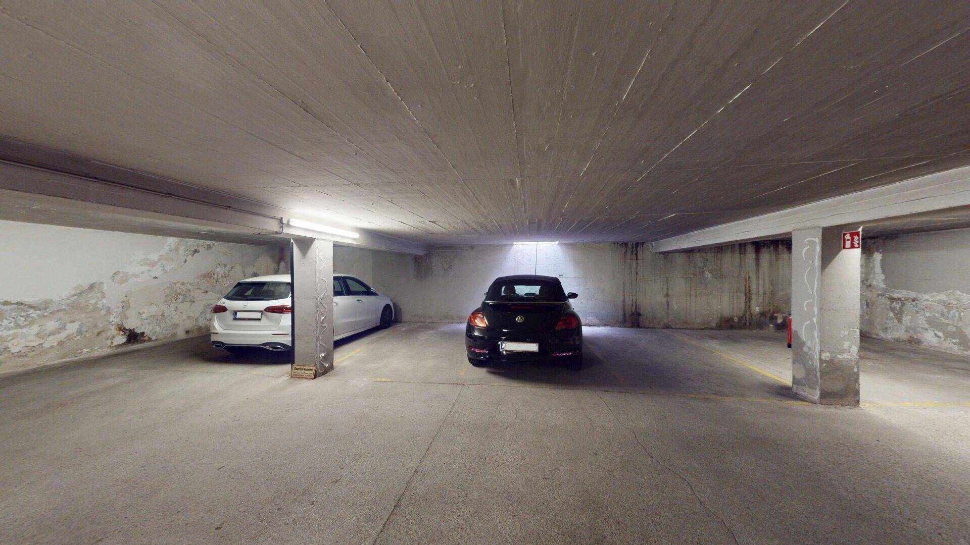 Tiefgarage mit zwei geparkten Autos und Betonwänden.