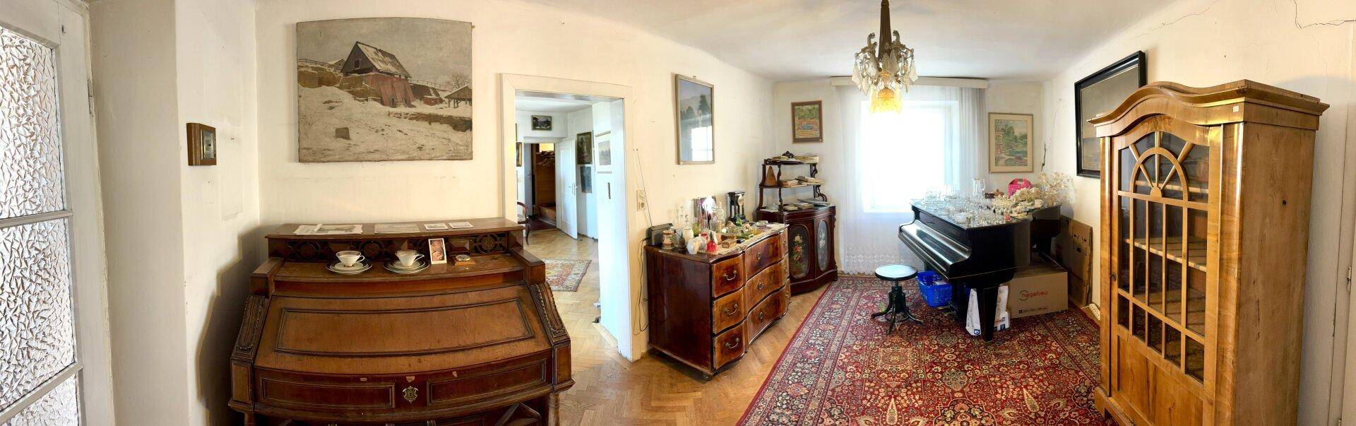 Geräumiges Zimmer mit Klavier, Teppichboden und antiken Holzmöbeln.