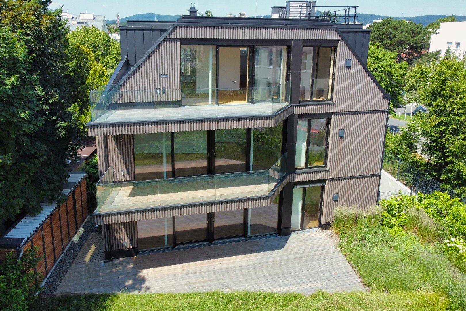 Gesamtansicht des modernen Gebäudes mit seinen Terrassen und der umliegenden Grünfläche.